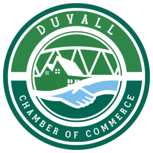 Logo of Duvall Chamber of Commerce featuring a green circle, two shaking hands, and images of a bridge and houses. - Duvall Chamber