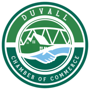 Green and white circular logo with "Duvall Chamber of Commerce" text. Features a handshake, a house, and trees. - Duvall Chamber