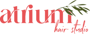 Logo with the words "atrium hair studio" in red and a green leafy branch design above the text. - Duvall Chamber
