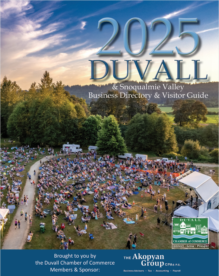 A large outdoor event with many people seated on a grassy field surrounded by trees, white tents, and a stage under a clear sky at sunset. Text overlay reads “2025 Duvall & Snoqualmie Valley Business Directory & Visitor Guide.”. - Duvall Chamber